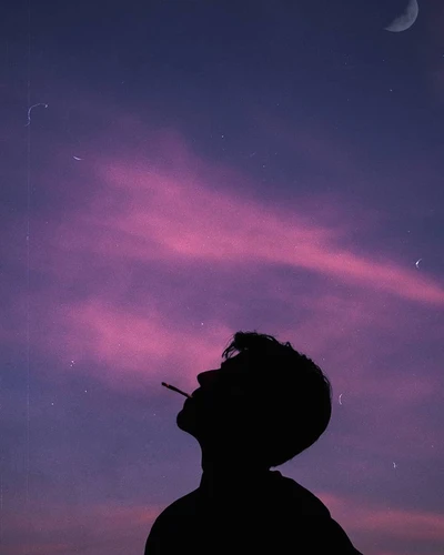 Silhouette d'un homme fumant sous un ciel nocturne rêveur