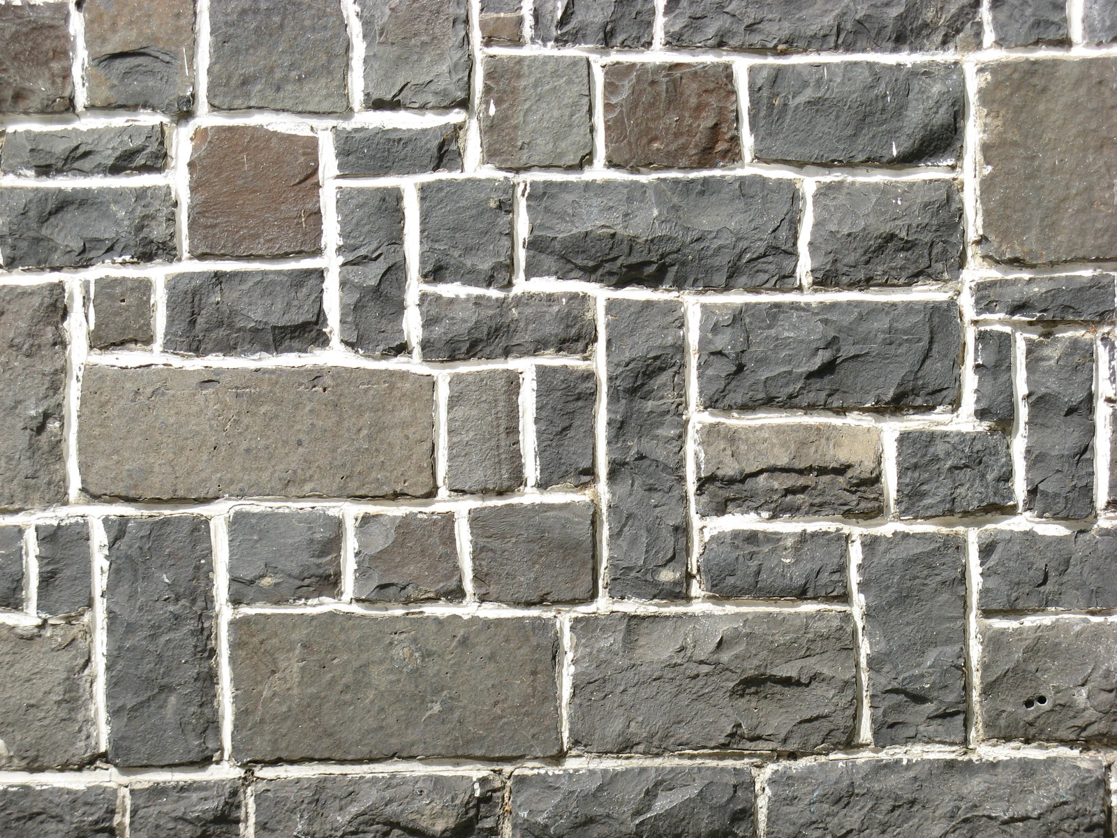 A close up of a brick wall with a fire hydrant in front of it (wall, brick, brickwork, stone wall, rock)