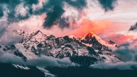 Montagnes majestueuses couvertes de neige sous des nuages dramatiques au crépuscule