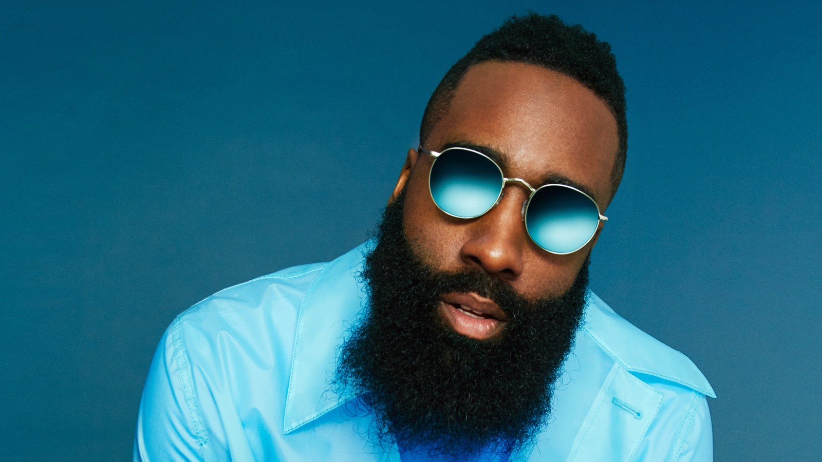 Uma girafa com barba e óculos de sol em um fundo azul (james harden, houston rockets, nba, óculos, cabelo facial)