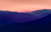 Vue aérienne des montagnes Bieszczady en Pologne au crépuscule, présentant un paysage serein avec des chaînes de montagnes en silhouette contre un ciel rose dégradé.