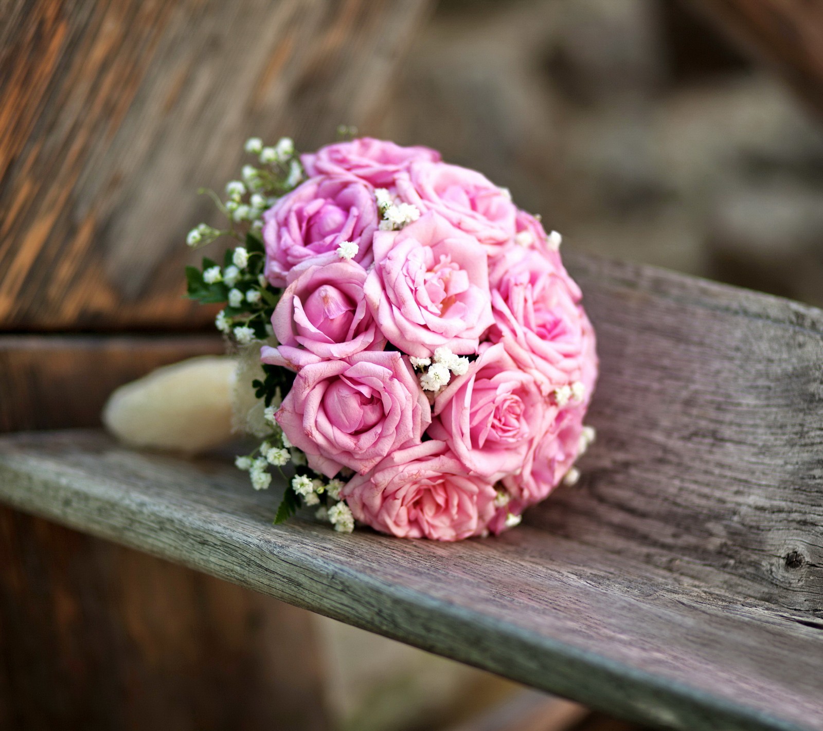 Un bouquet de roses roses posé sur un banc (bouquet, fleurs, rose, roses, mariage)