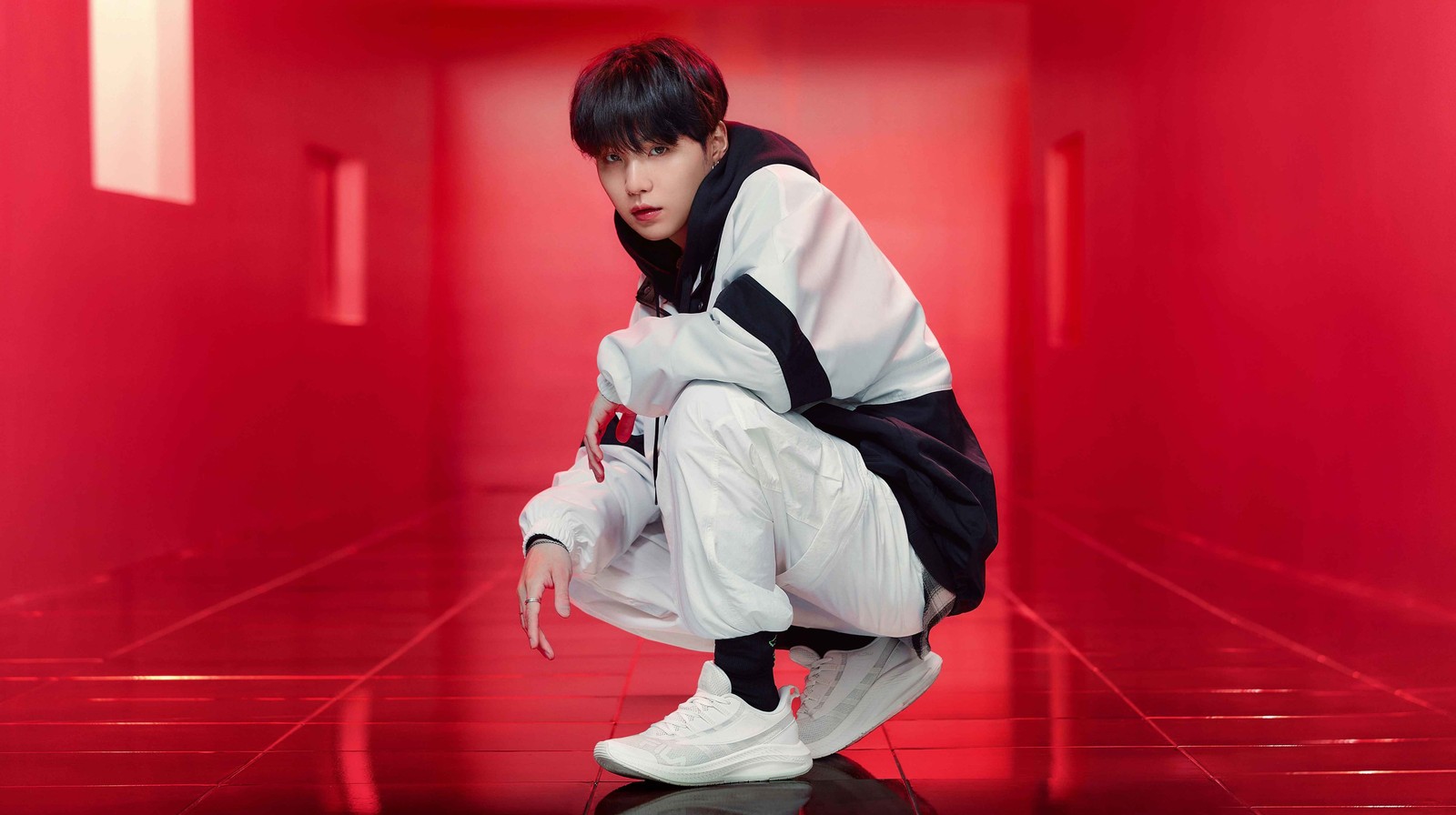 A close up of a person squatting on a red floor (bts, suga)