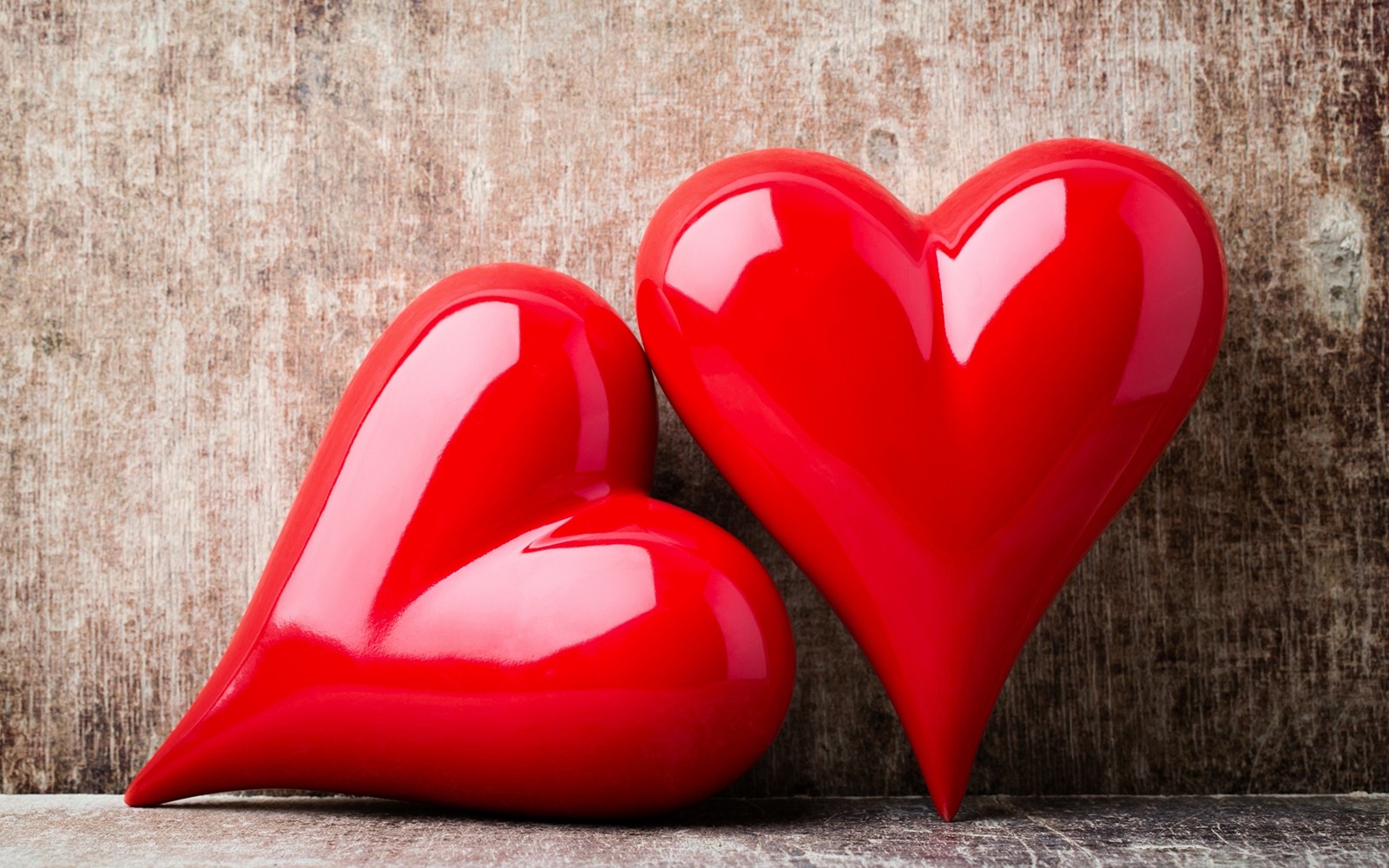 Deux cœurs rouges sur une surface en bois avec un mur en arrière-plan (cœur, rouge, amour, saint valentin)