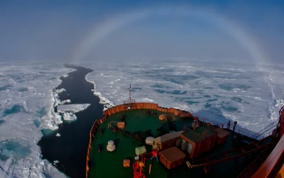 Navio navegando por campos de gelo sob um céu ártico colorido