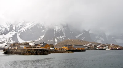 Charmantes Küstendorf, umgeben von schneebedeckten Bergen in Lofoten