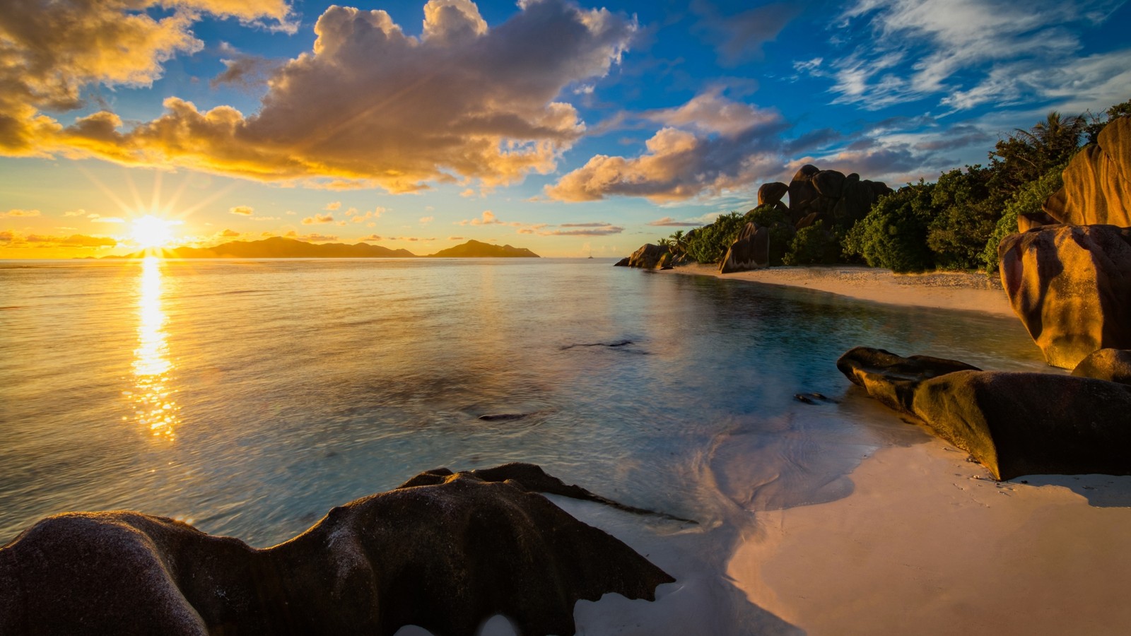 Uma praia com rochas e água ao pôr do sol com o sol se pondo (praia, maldivas, mar, costa, nuvem)