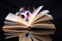 Découpe en forme de cœur dans un livre ouvert avec un fond bokeh coloré