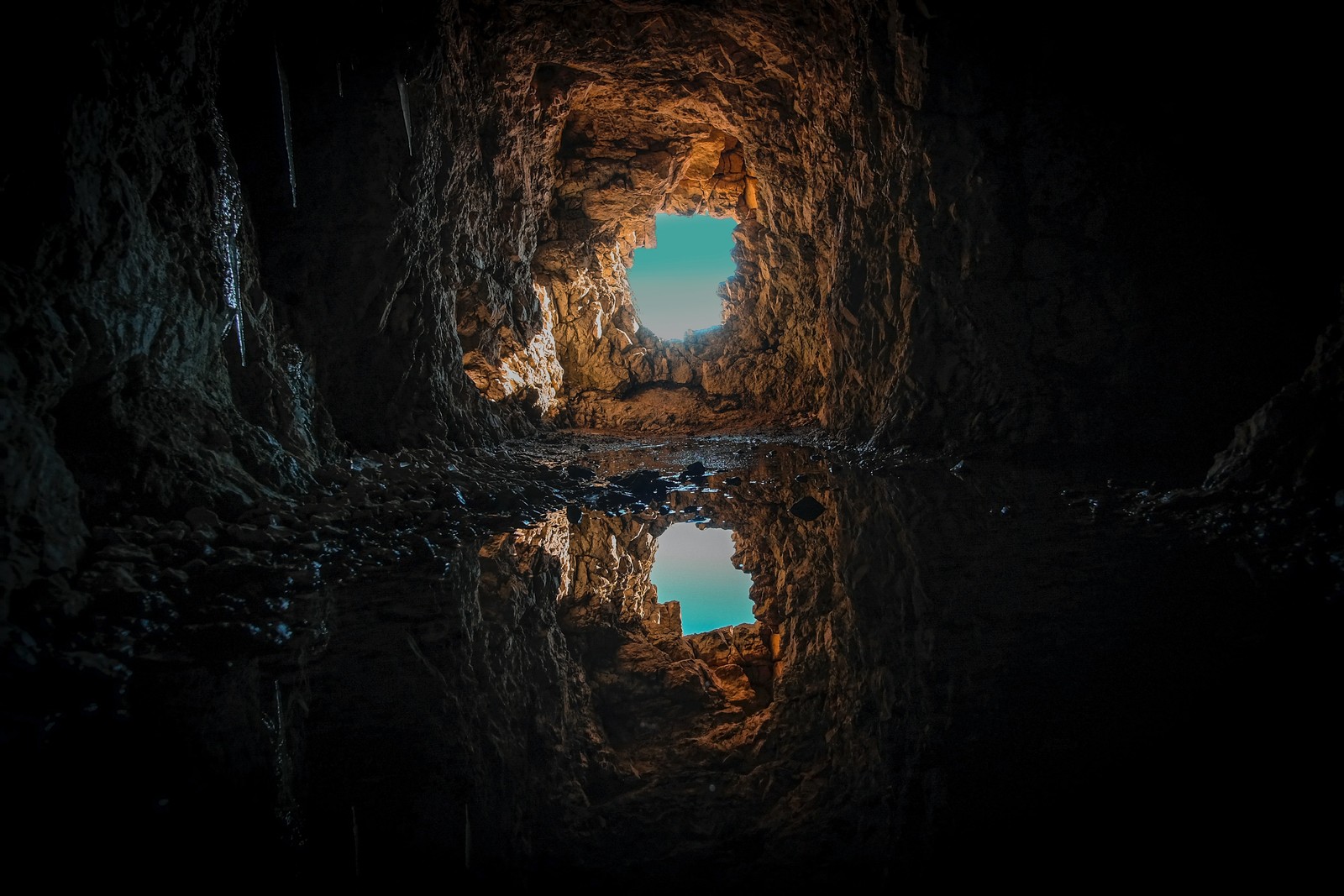 Eine aussicht auf eine höhle mit der reflexion des himmels im wasser (höhle, tunnel, reflexion, wasser, symmetrisch)