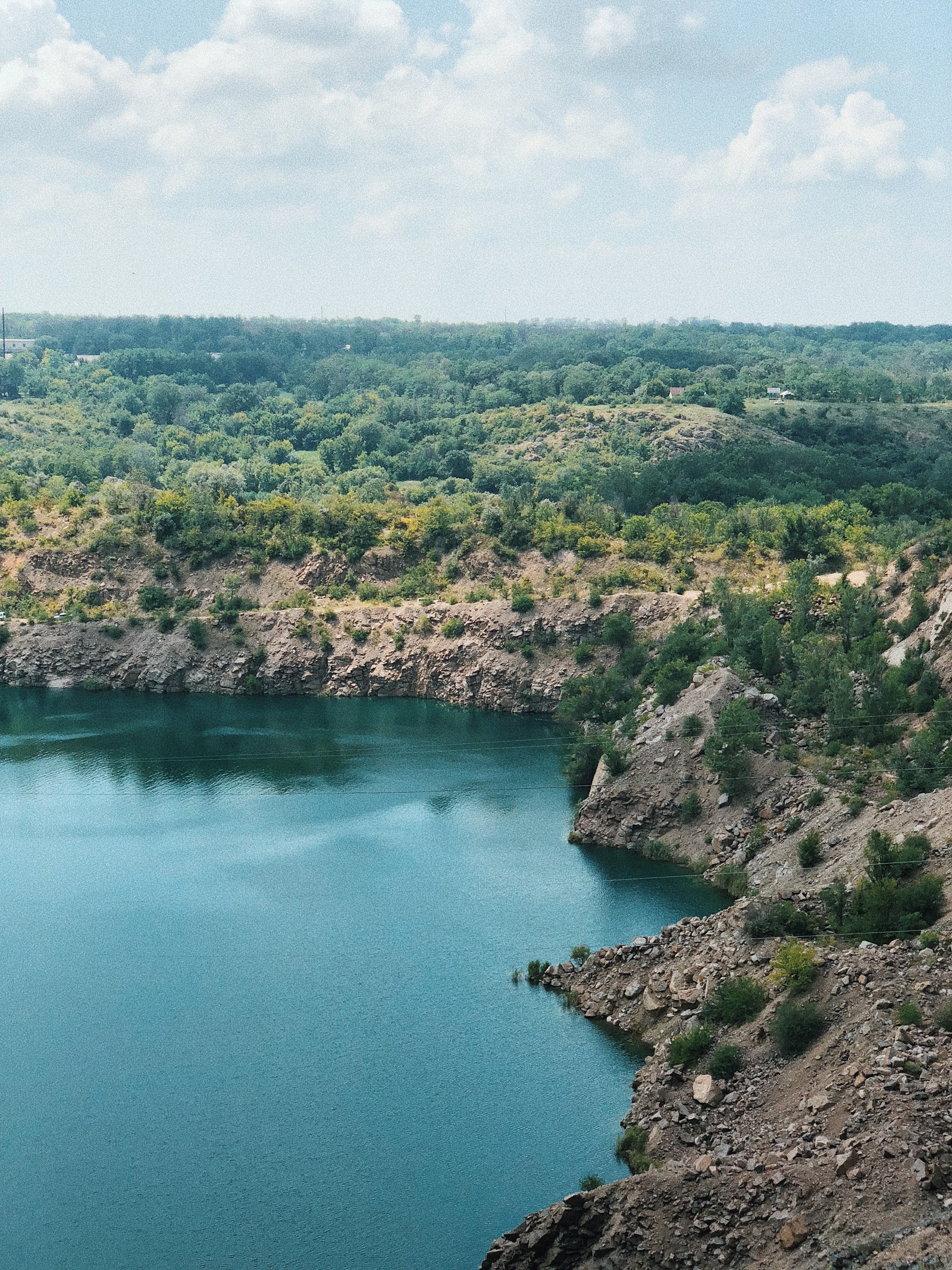 There is a man that is standing on a rock by the water (nature reserve, crater lake, reservoir, water resources, national park)