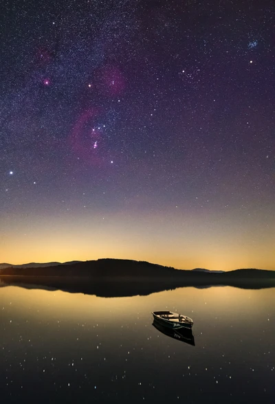 Serene Nightscape: A Boat on a Tranquil Lake Under the Milky Way