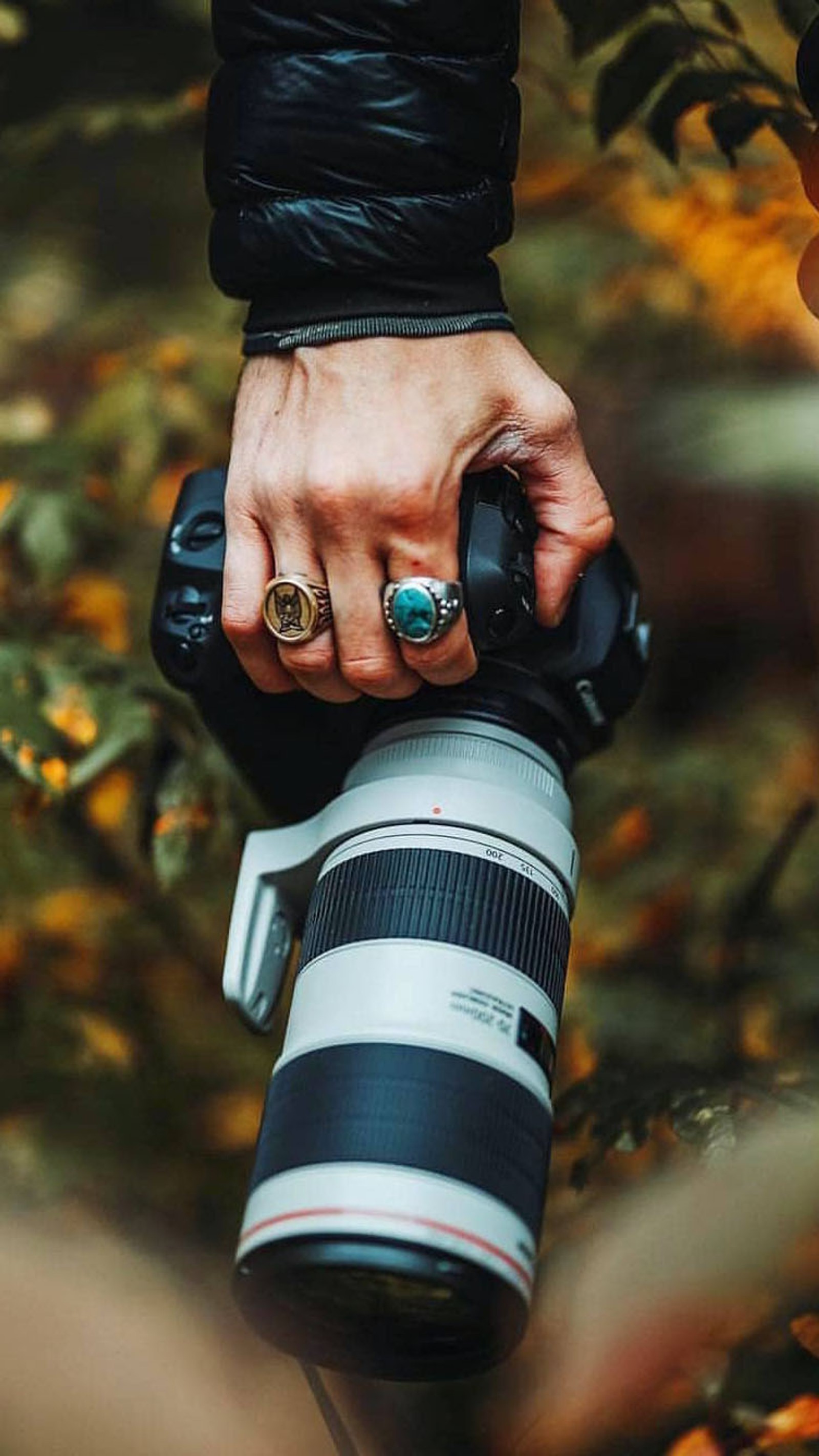 Alguien sosteniendo una cámara con un anillo en su dedo (canon, cámara, lente, ángulo amplio, peter mckinnon)