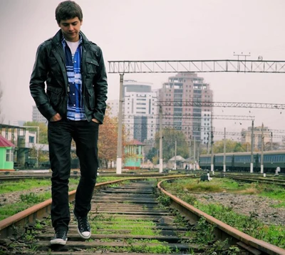 A thoughtful boy walks along train tracks, lost in reflection amidst an urban backdrop.