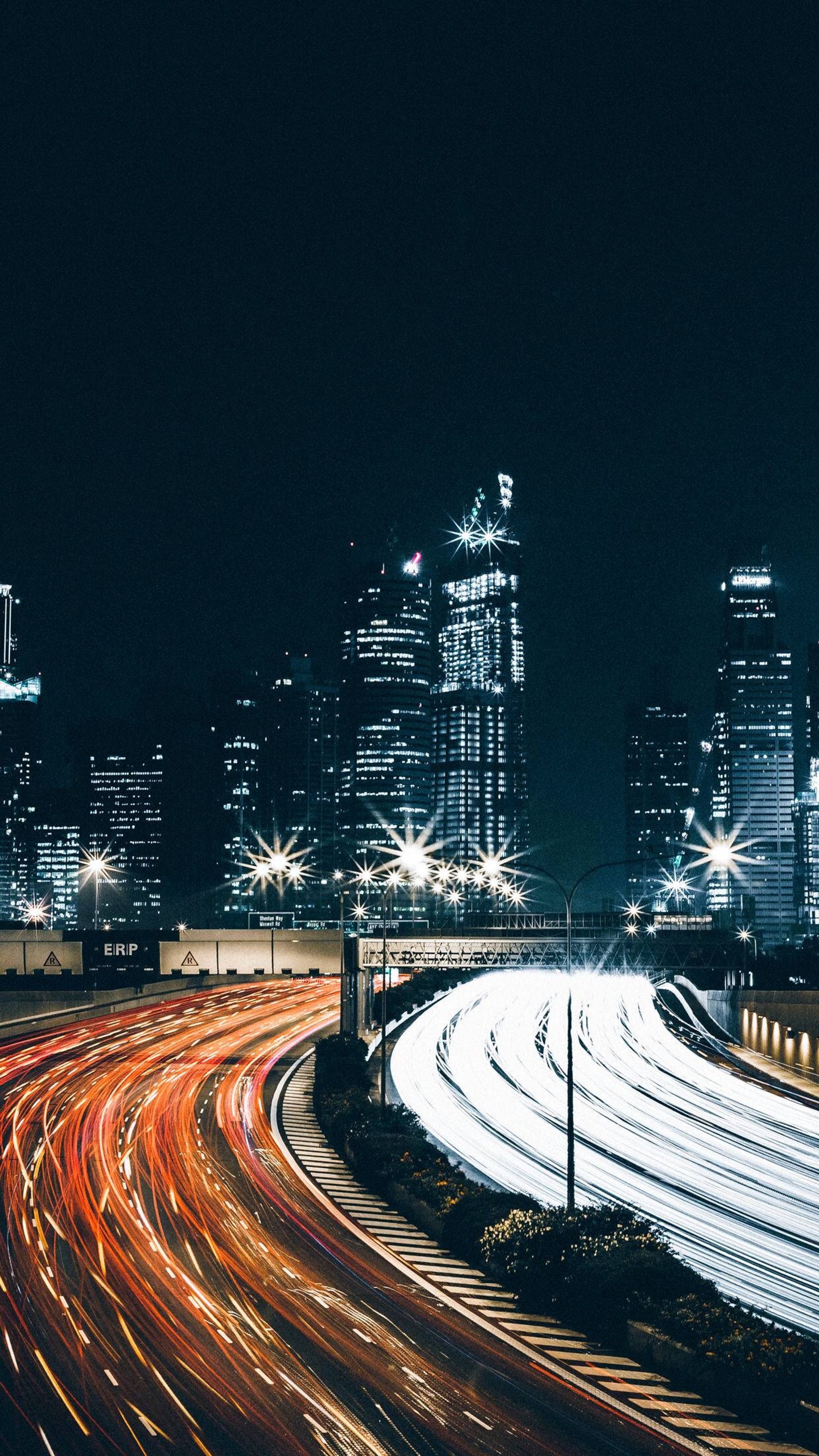 Vista aérea de uma cidade à noite com uma rodovia e uma estrada rápida (natureza, praia, edifício, arranha céus, eletricidade)