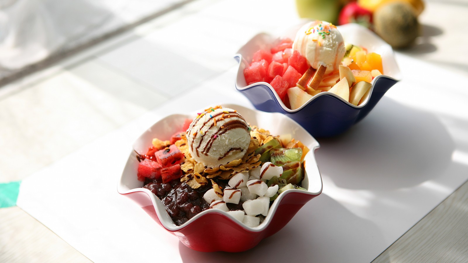 There are two bowls of food on a table with fruit (sundae, frozen dessert, food, dairy product, fruit)