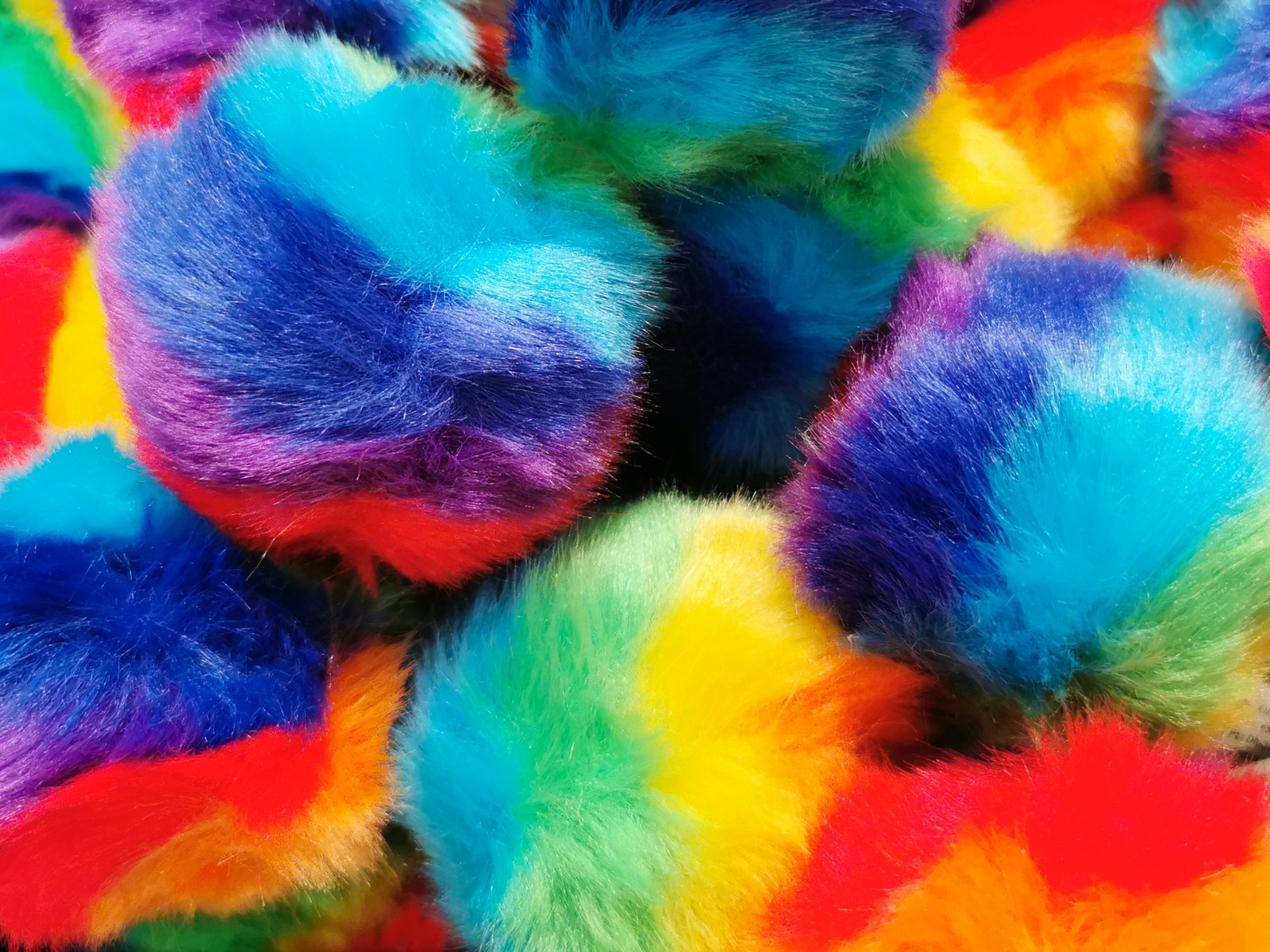 Um close de um monte de bolas fofas multicoloridas (faux fur pom pom balls, multicolorido, colorido, macro, close up)