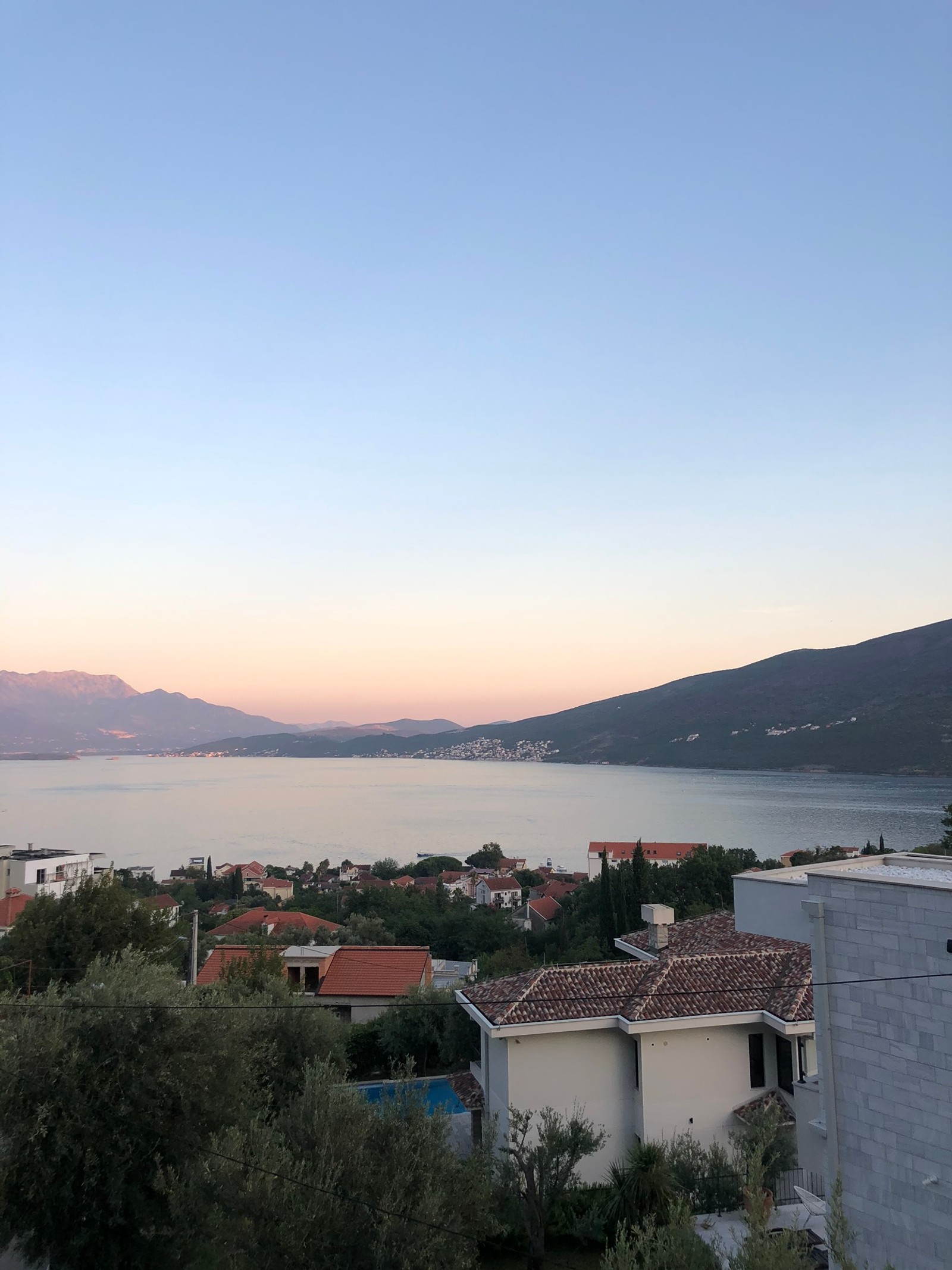 Vista aérea de uma cidade com um lago e montanhas ao fundo (imóveis, água, terras altas, horizonte, banco)