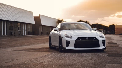 Sleek white Nissan GT-R parked in an urban setting at sunset, showcasing its sporty design and alloy wheels.