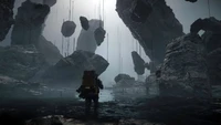 Une silhouette solitaire explore un paysage surréaliste et désolé rempli de rochers suspendus et d'une lumière éthérée, incarnant l'atmosphère étrange de "Death Stranding 2".