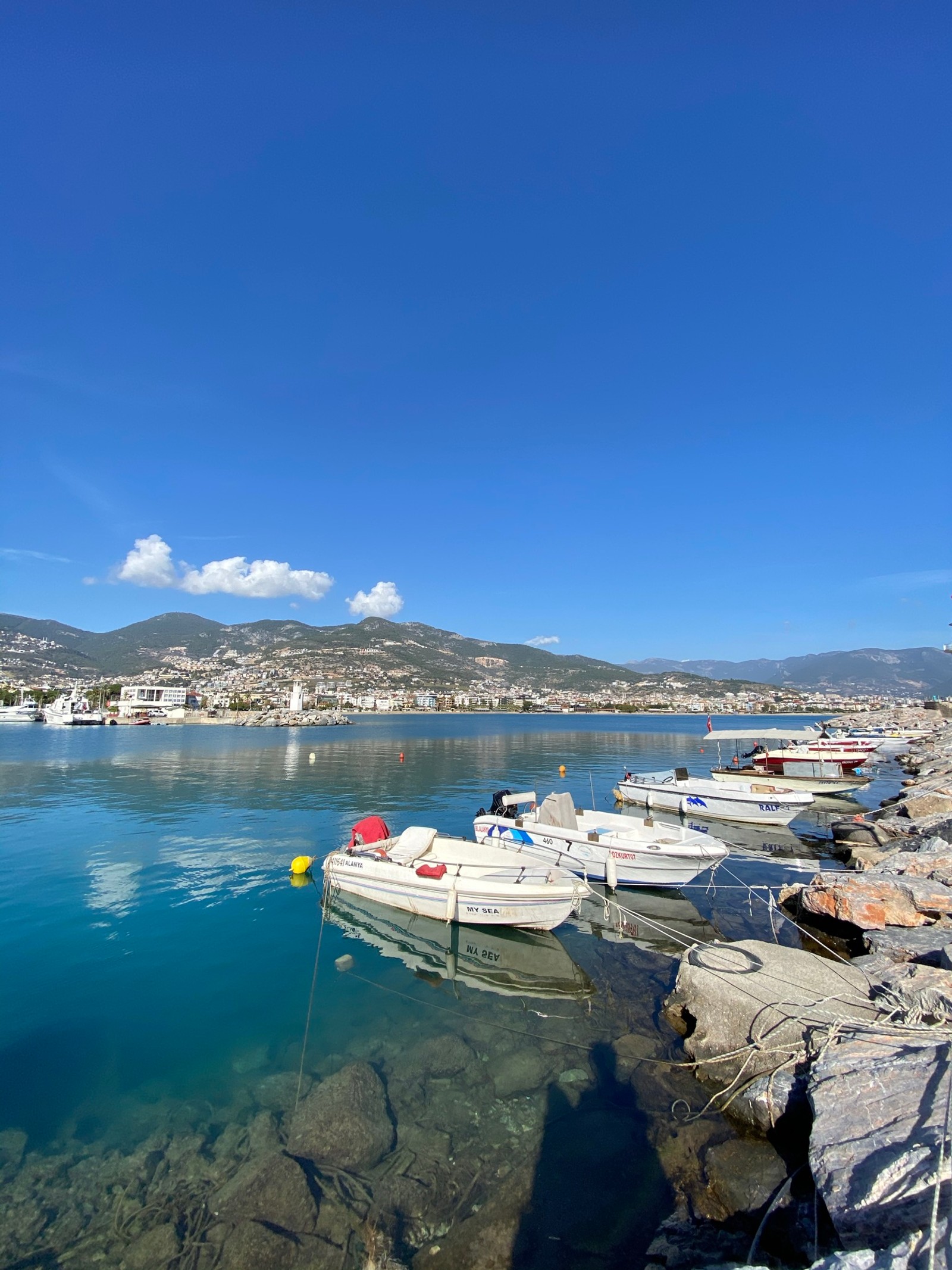 Las barcas están atracadas en las aguas claras de un puerto (agua, nube, barco, embarcación, lago)