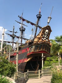 Majestuoso barco pirata con figura de calavera en medio de exuberantes palmeras.