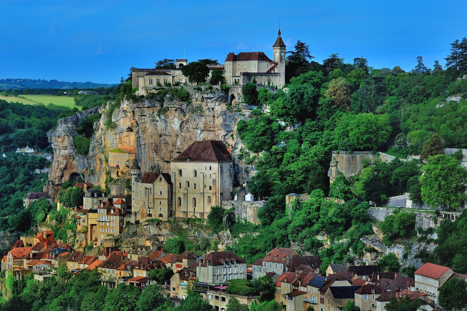 Eine ansicht eines dorfes auf einer klippe mit einer kirche oben. (bergdorf, dorf, stadt, burg, touren)