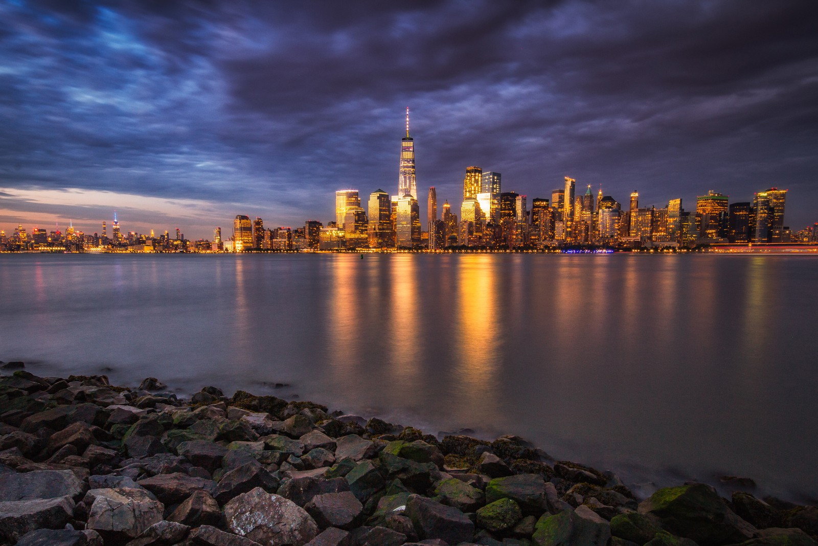 Una vista del horizonte de la ciudad desde el agua por la noche (one world trade center, paisaje urbano, ciudad, panorama, área urbana)