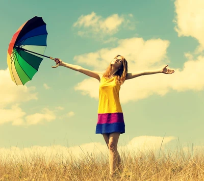 Menina alegre com guarda-chuva multicolorido em um campo ensolarado