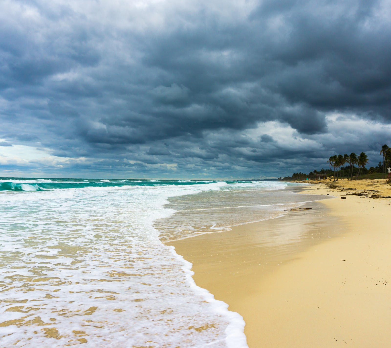 Un cielo nublado sobre una playa con olas y palmeras (playa, cuba)