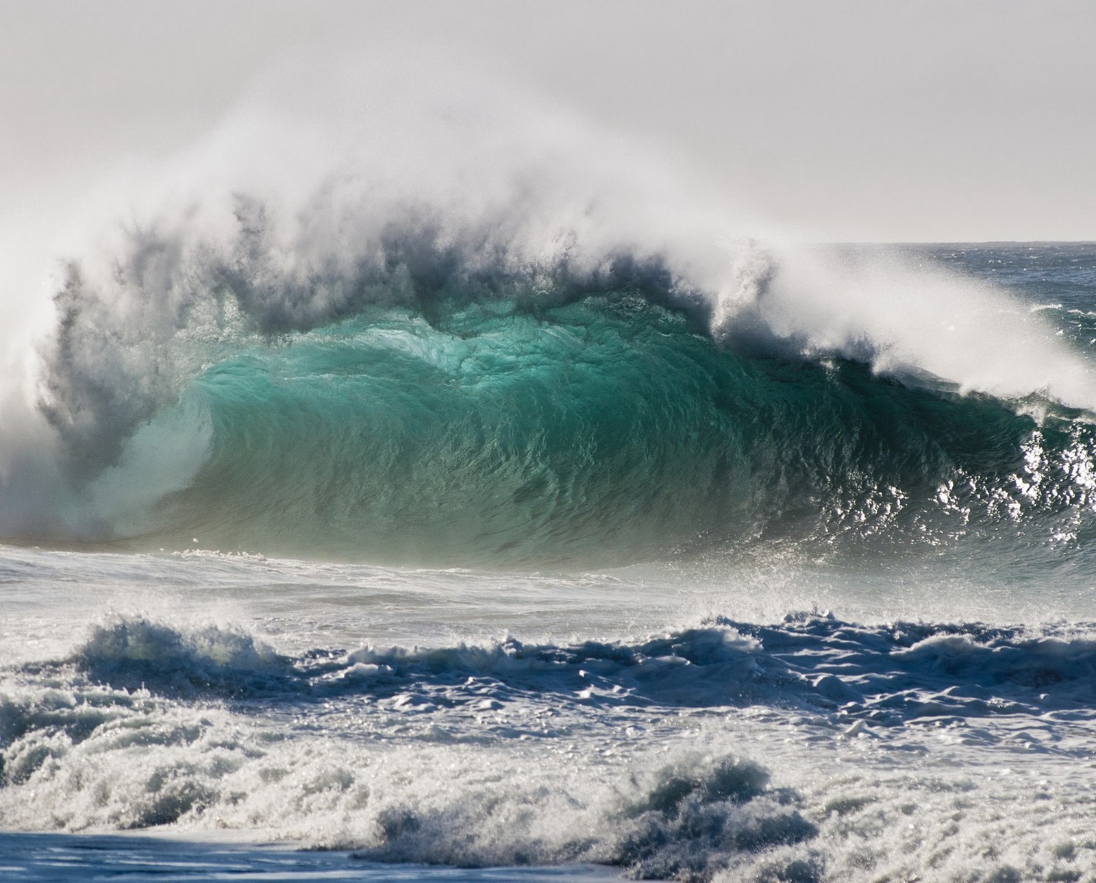 Surfer riding a large wave in the ocean on a cloudy day (breaking wave, hawaii, kauai)