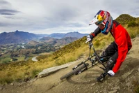 Freeride-Downhill-Mountainbiker, der einen steilen Hang in einer bergigen Landschaft navigiert.