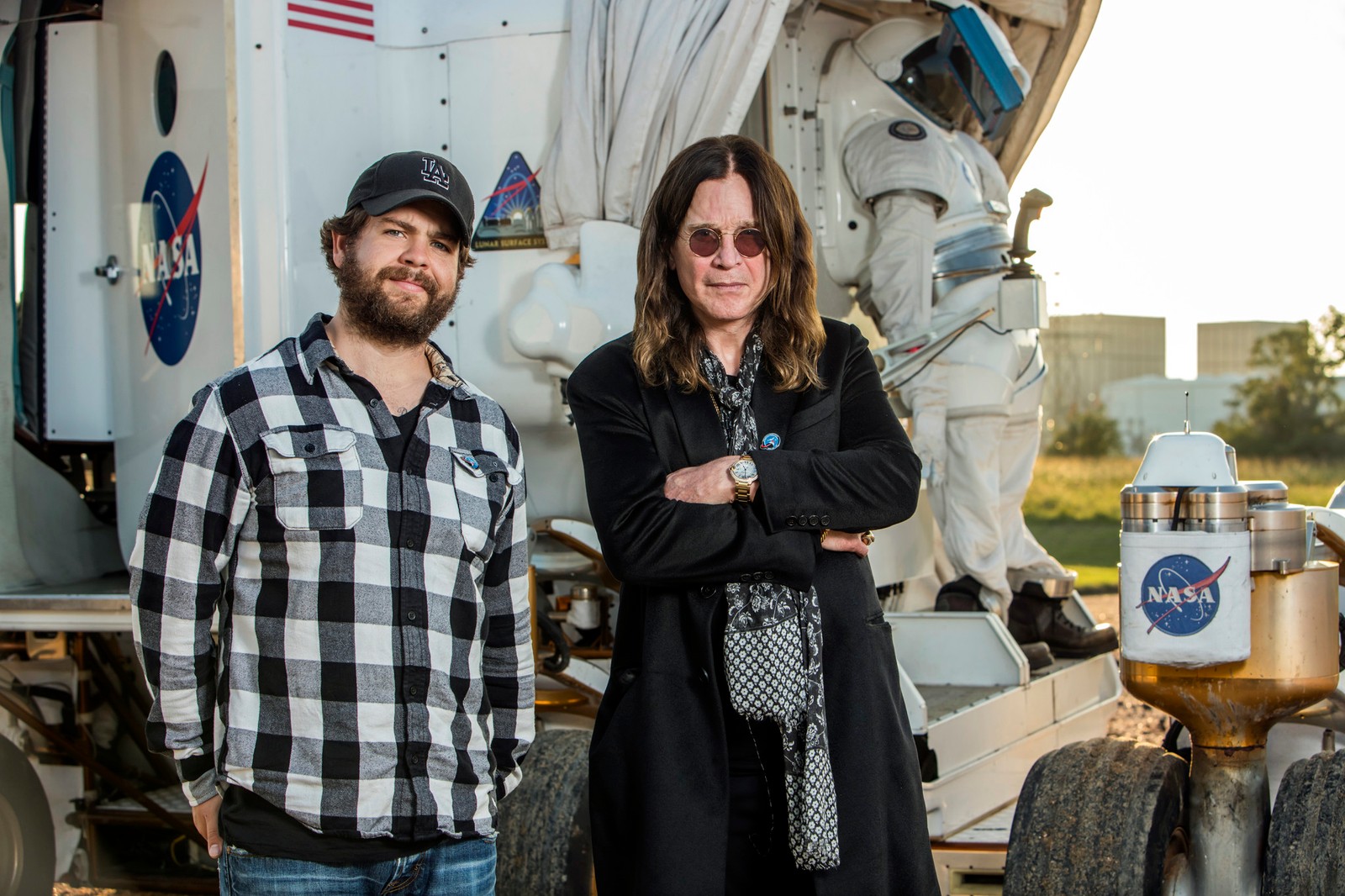 Two men standing next to a truck with a space shuttle on it (the osbournes, history, black sabbath, event, car)