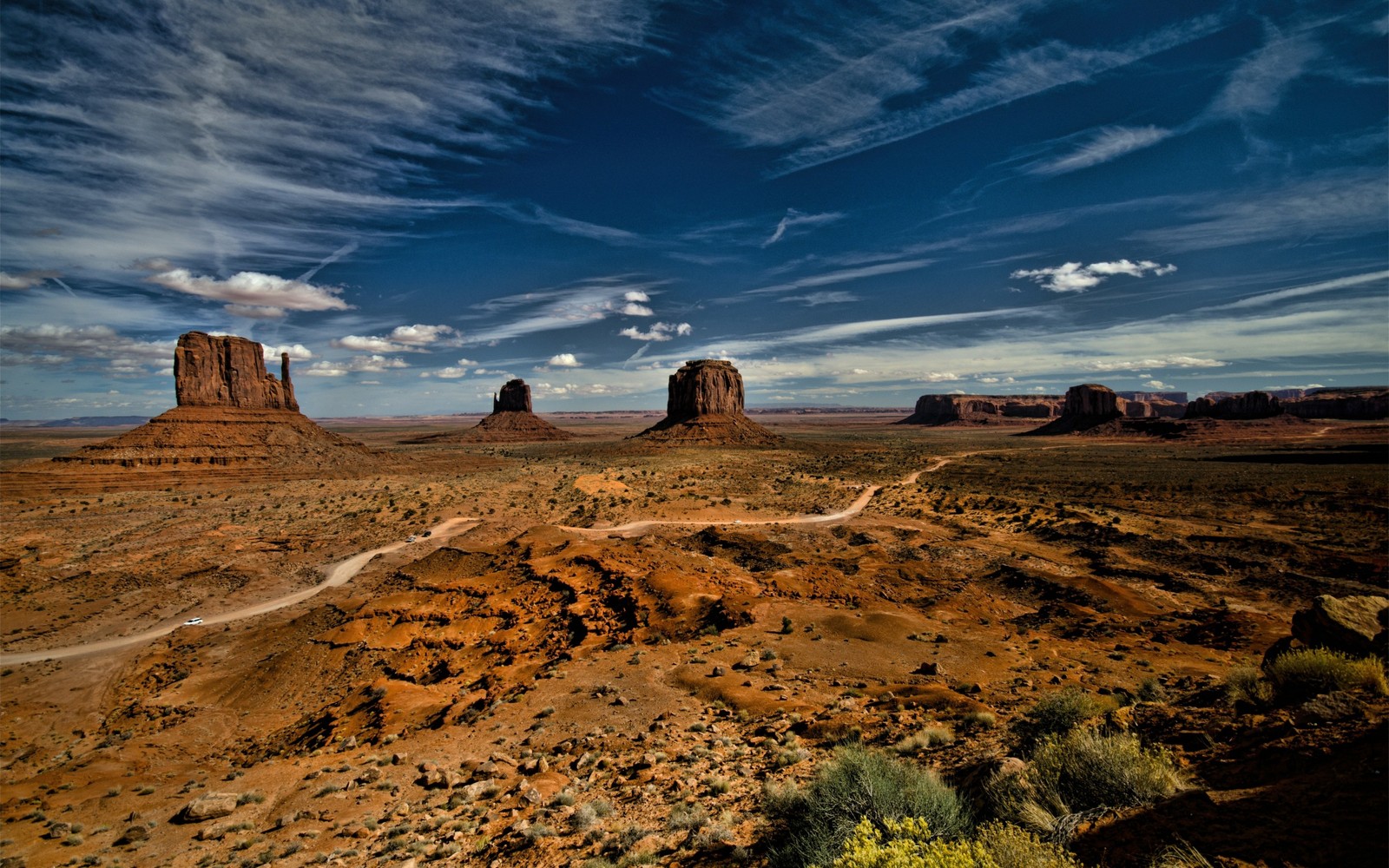 Uma vista do deserto com uma estrada de terra em primeiro plano (monument valley, vale, nuvem, butte, rocha)