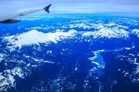 Impresionante vista aérea de montañas cubiertas de nieve y océano bajo un cielo nublado