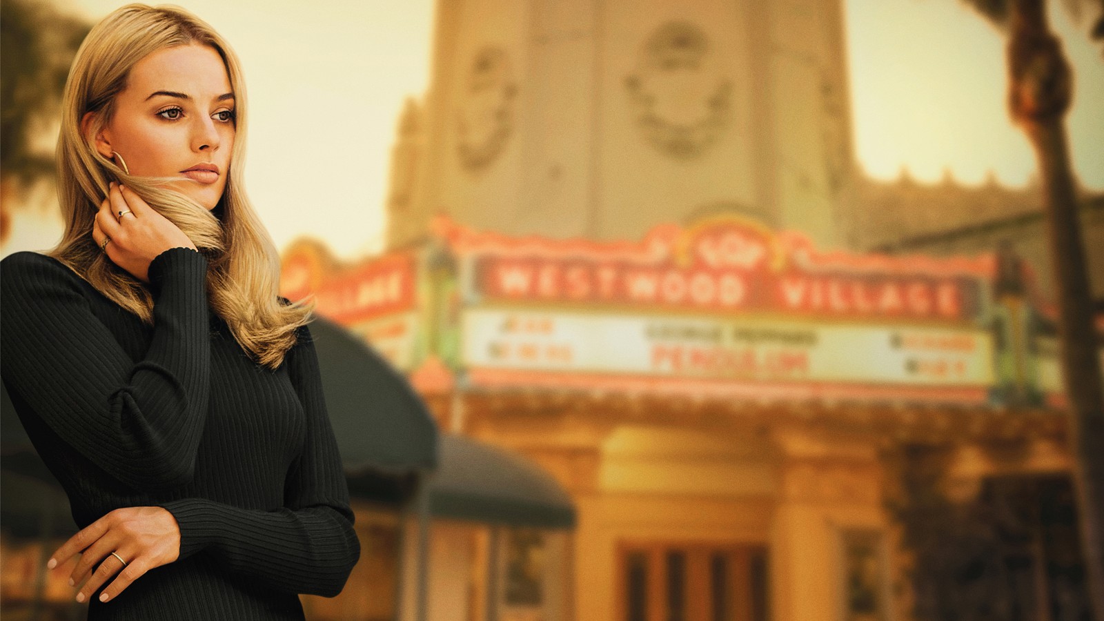 Une femme blonde en robe noire se tient devant un théâtre (margot robbie, blond, quentin tarantino, film, beauté)