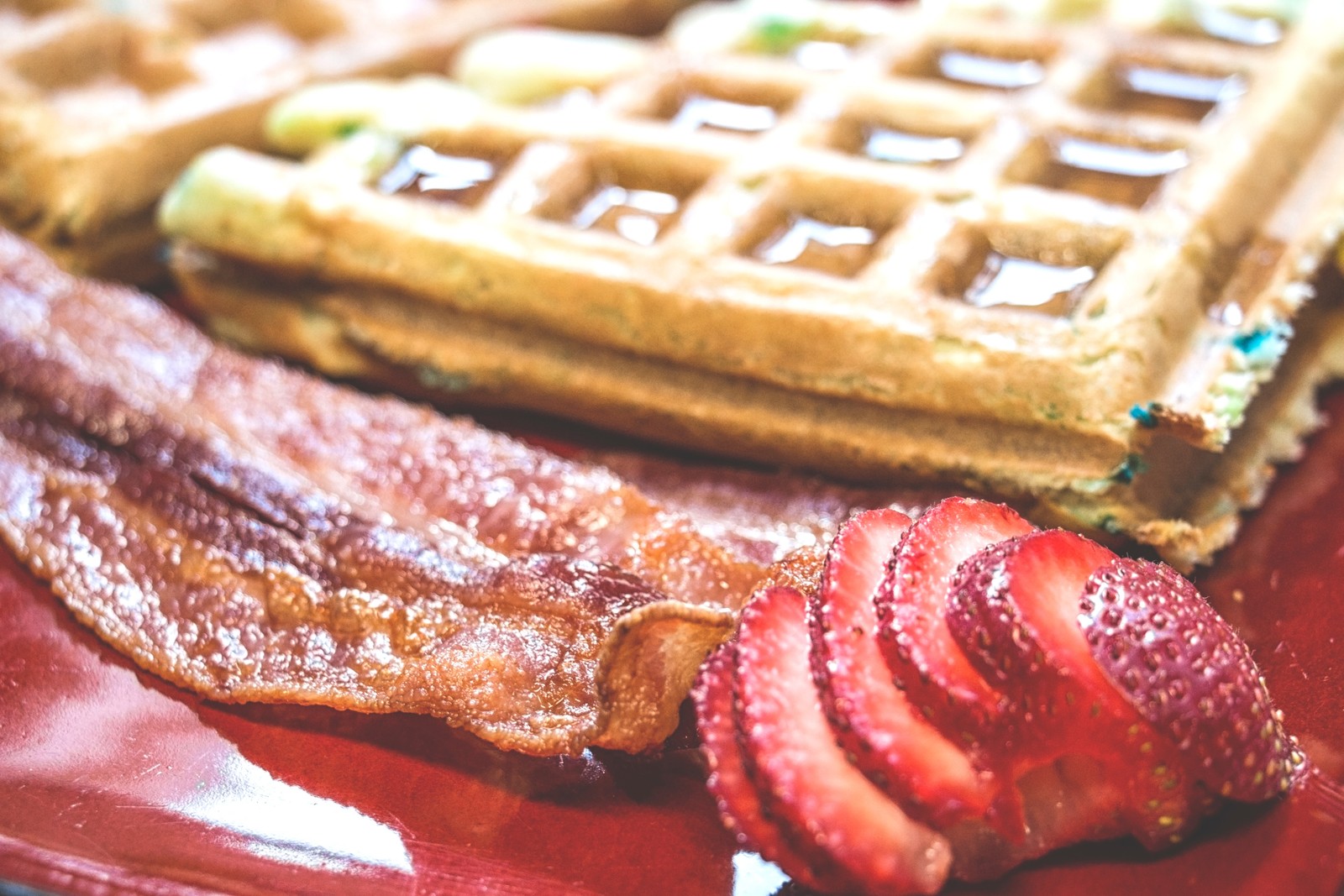 Un primer plano de un waffle con tocino y fresas en un plato (waffle, platos, comida, crema, ingrediente)