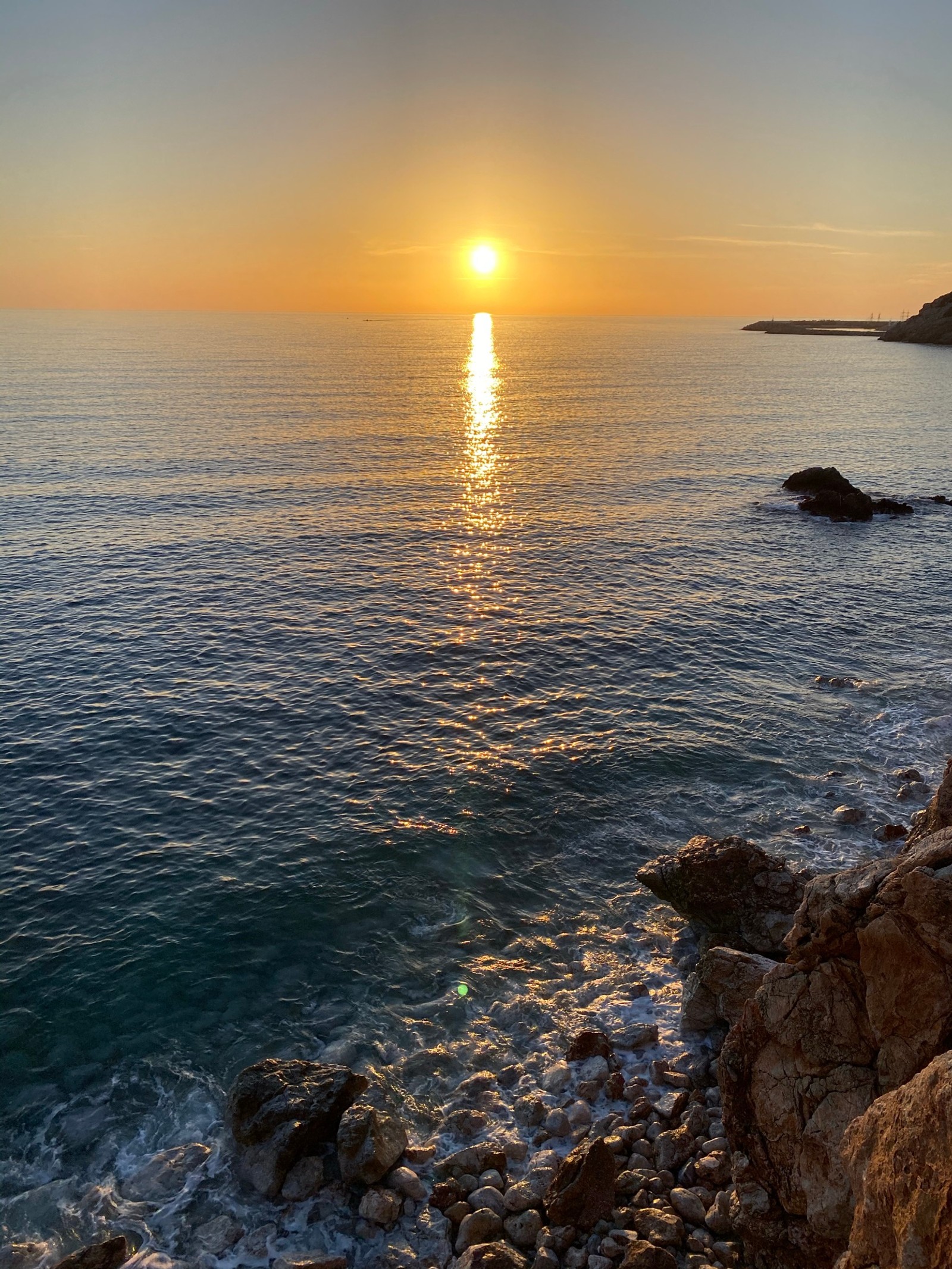 Vue sur un coucher de soleil sur l'océan avec des rochers et de l'eau (mer, eau, ressources en eau, atmosphère, journée)