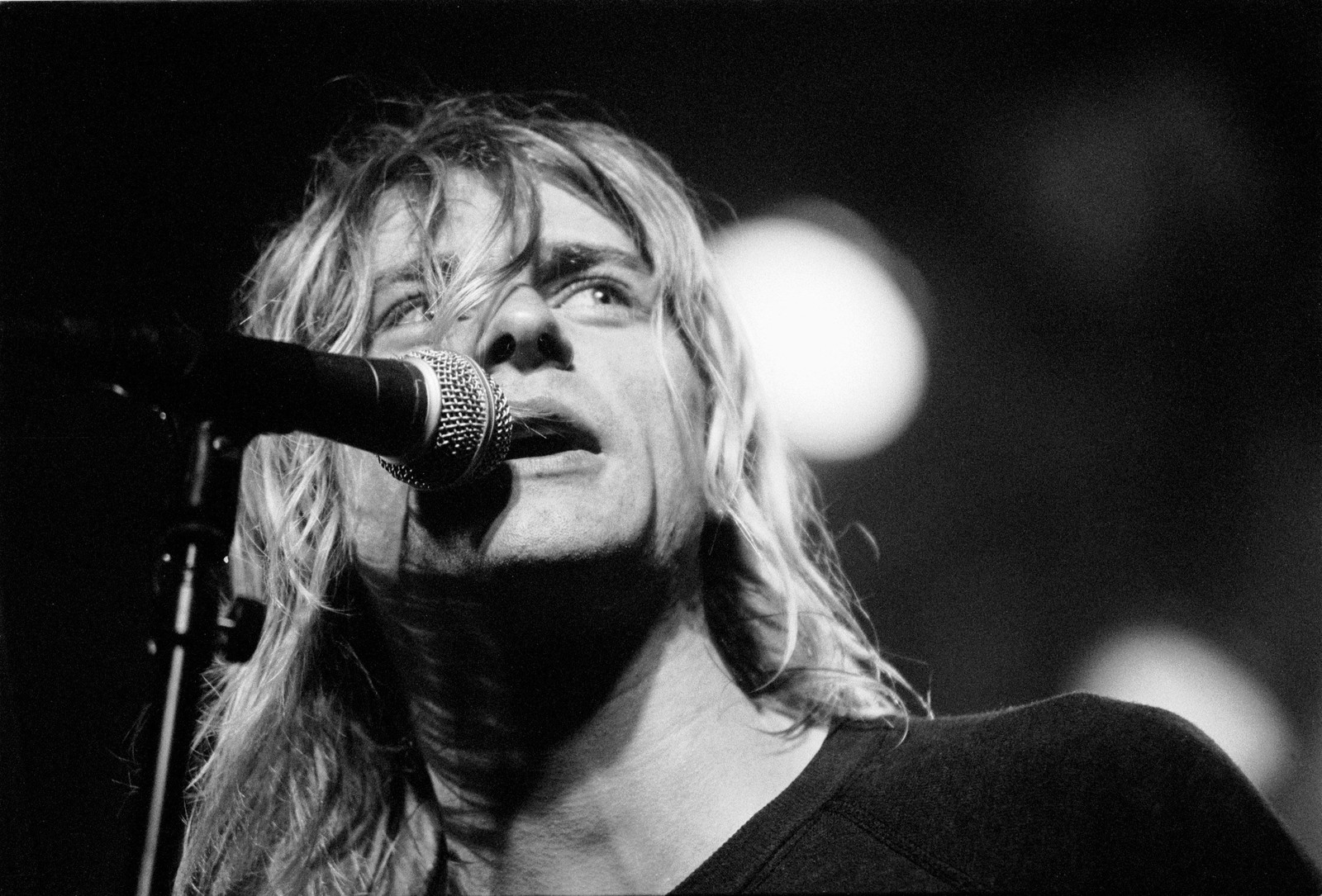 Arafed image of a man with long hair singing into a microphone (nirvana, grunge, performance, singing, entertainment)