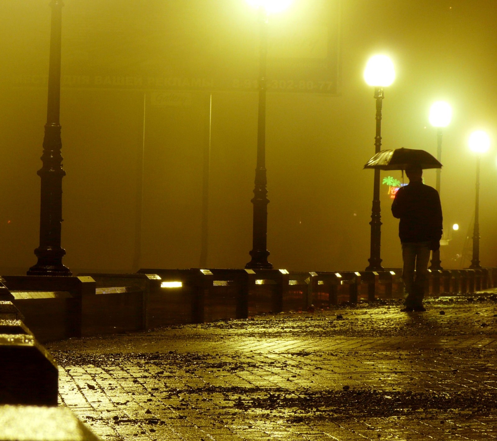 Uma pessoa caminhando pela calçada com um guarda-chuva (anoitecer, homem, chuva)