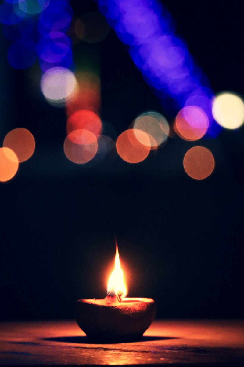 Крупный план горящей свечи на столе с размытым фоном (боке, bokeh, свеча, candlelight, дивали)