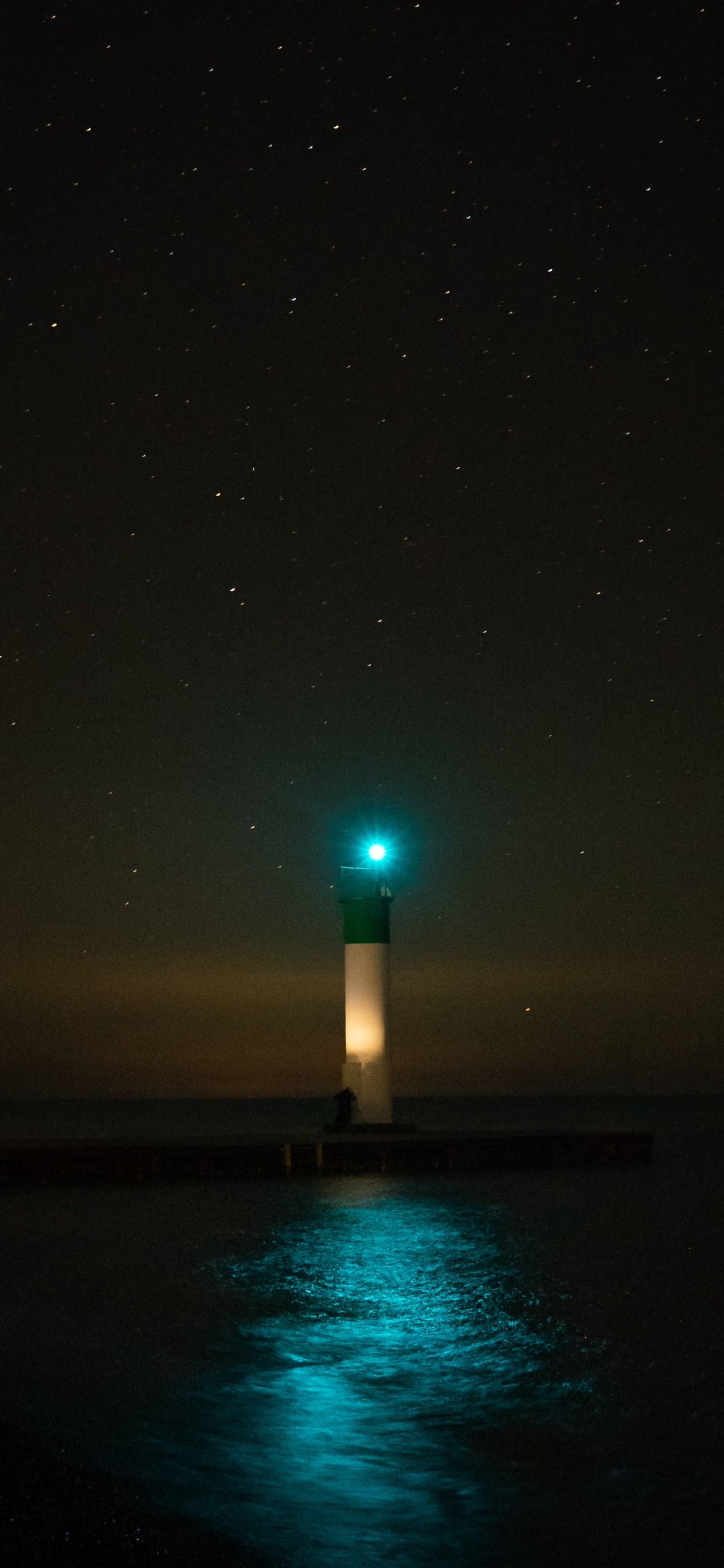 Um belo farol com luz verde em uma noite escura (água, farol, atmosfera, poste de luz, torre)