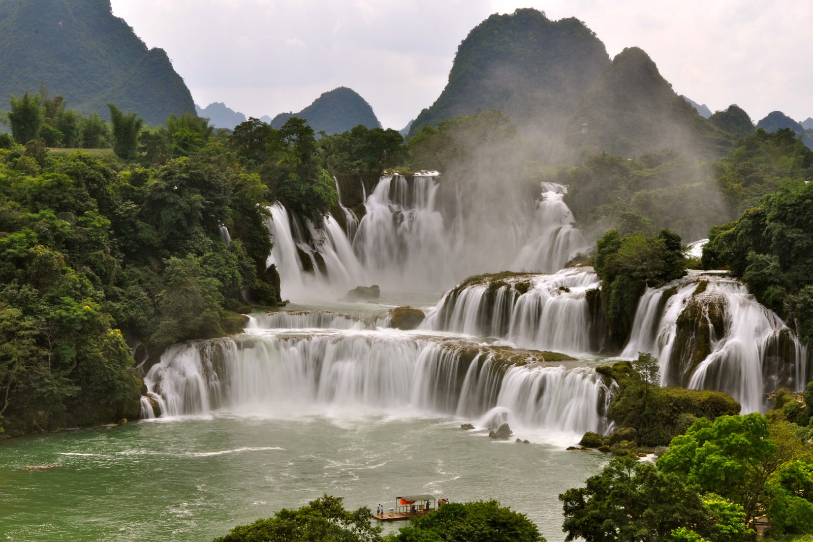 Une cascade au milieu d'une rivière avec un bateau au milieu (chutes de lange, la cascade, ressources en eau, plan deau, nature)