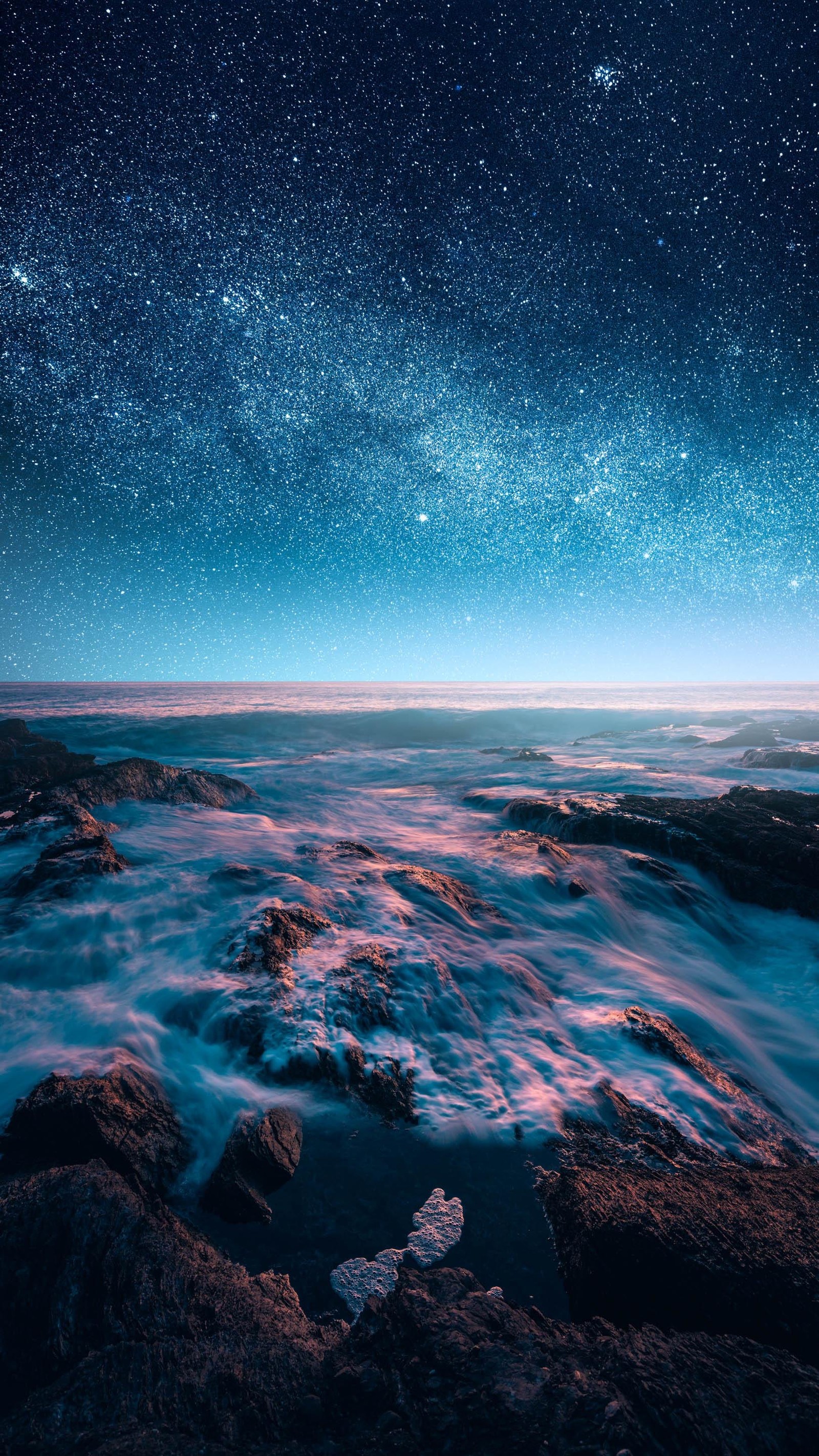 Céu noturno estrelado sobre o oceano com pedras e água (água, atmosfera, recursos hídricos, paisagem natural, azul)