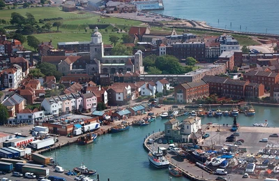 Aerial view of a vibrant harbor town with colorful buildings, boats, and a scenic waterfront in an urban setting.