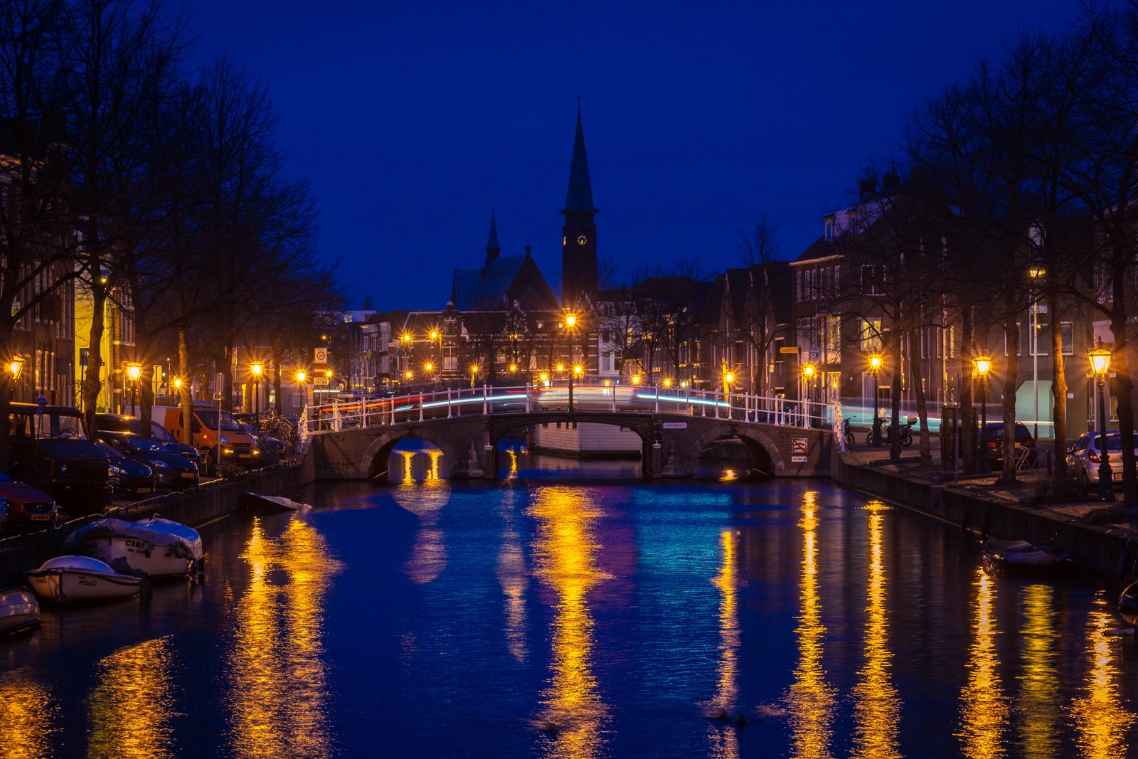 Imagem desfocada de uma ponte sobre um canal com barcos e edifícios ao fundo (cidade, via navegável, noite, canal, reflexo)