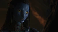 Un personnage Na'vi avec une peau bleue frappante et des bijoux complexes, exprimant une profonde émotion dans un moment clé de "Avatar : La voie de l'eau".