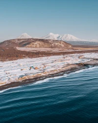 Ruhige arktische Küste mit schneebedeckten Bergen und ruhigem Hafen