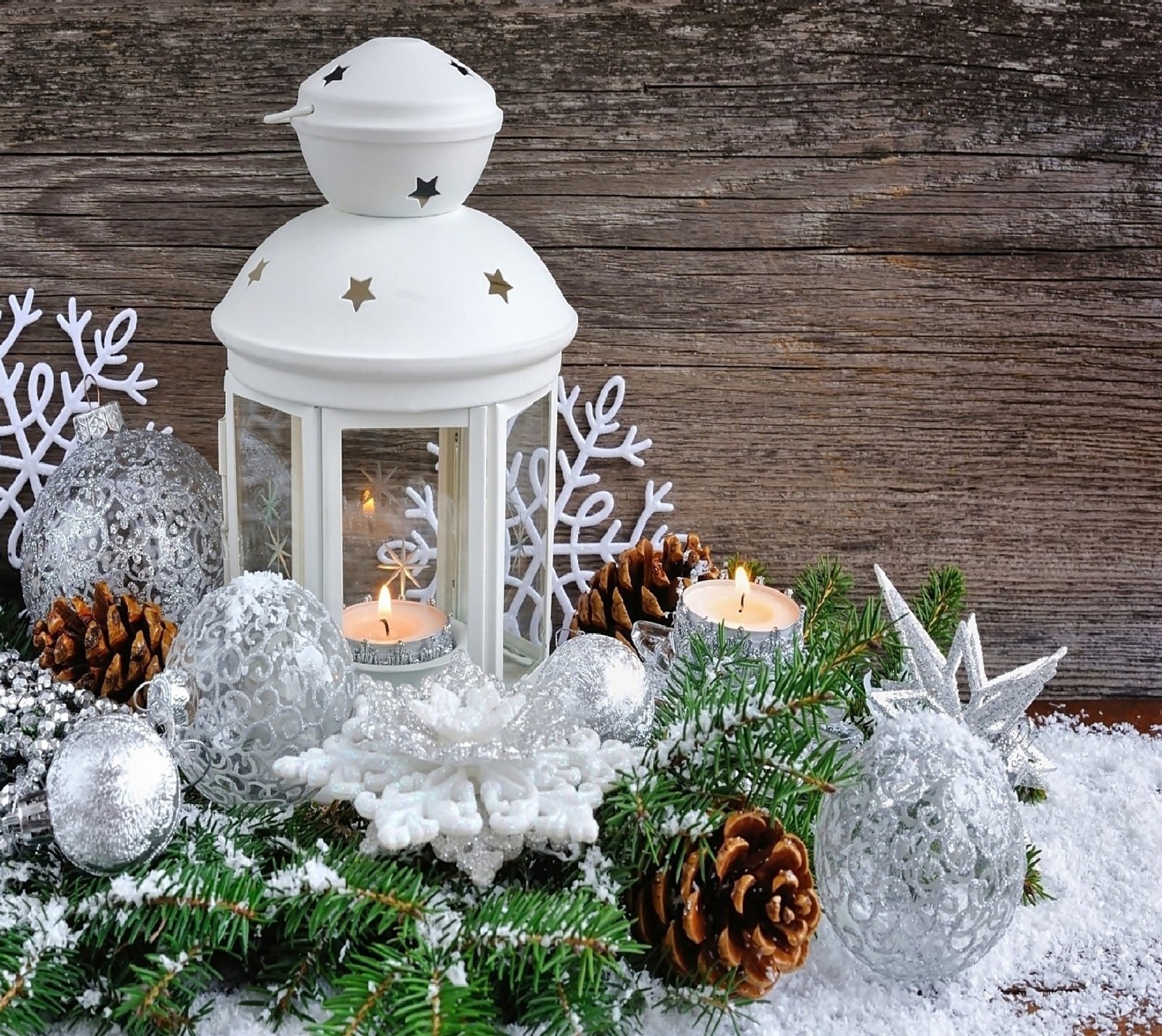 There is a white lantern with a candle and some pine cones (nature)