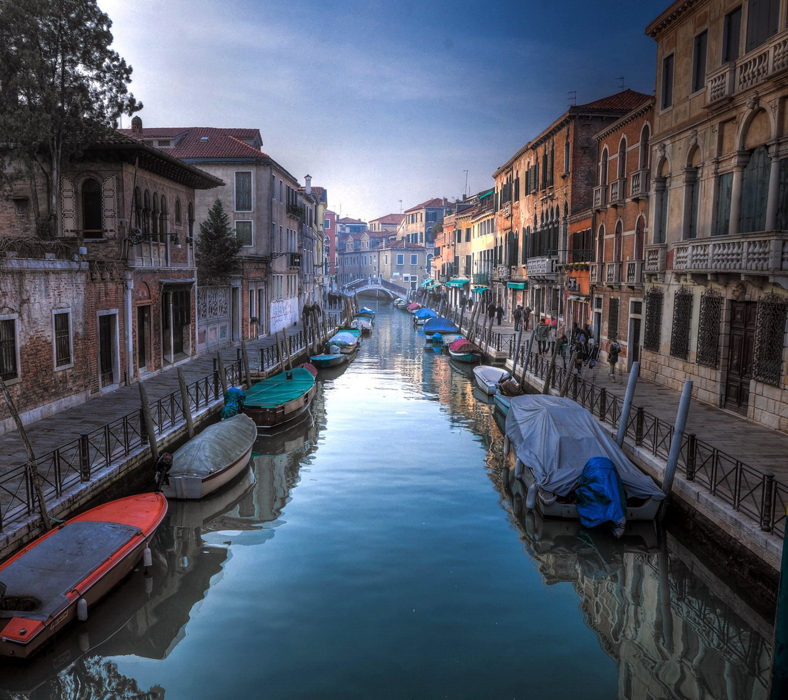 Barcos estão atracados ao lado de um canal em uma cidade (itália, veneza, venezia)