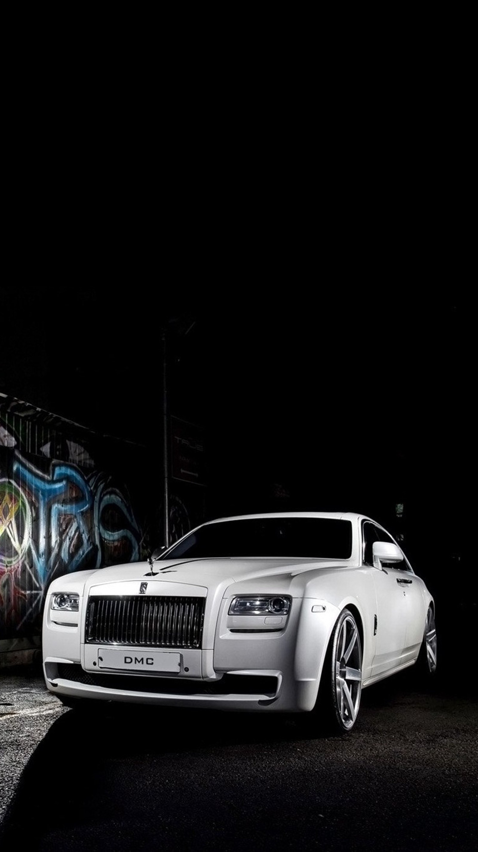 A close up of a white car parked in front of a graffiti covered wall (amazing, car, rolls royce)